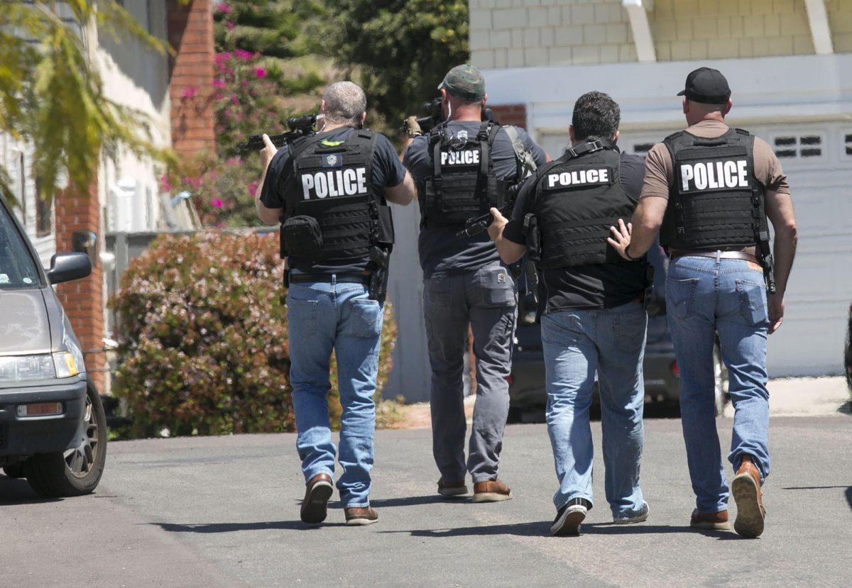 Heavily armed San Diego police officers approach a house thought to be the home of 19-year-old John T. Earnest, in San Diego, on April 27, 2019. (John Gibbins/The San Diego Union-Tribune via AP)