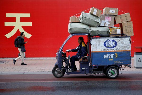 An electric delivery vehicle of Deppon Logistics drives past a banner with a government slogan in Beijing on Nov. 6, 2018. (Thomas Peter/Reuters)