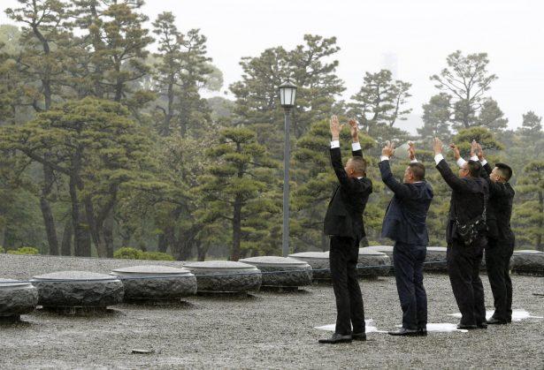 People raise their arms in the air toward Imperial Palace in Tokyo Tuesday, April 30, 2019. Japanese ruler Akihito is set to abdicate later in the day. (Shinji Kita/Kyodo News via The Associated Press)