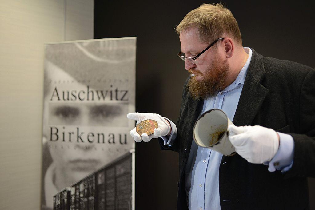 Piotr Cywinski, director of the Auschwitz-Birkenau museum, presents the metal mug with a double bottom in which a gold ring and necklace were found by employees of the museum in Oswiecim, Poland. (©Getty Images | <a href="https://www.gettyimages.com/detail/news-photo/piotr-cywinski-director-of-the-auschwitz-birkenau-museum-news-photo/532588128">BARTOSZ SIEDLIK</a>)