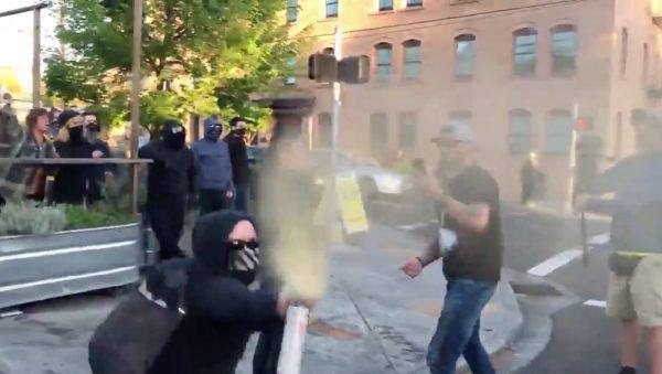 A masked alleged member of Antifa directs a stream of pepper spray, unprovoked, towards the face of journalist Andy Ngo outside the Cider Riot bar in Portland, Oregon, on May 1, 2019. (Courtesy of Andy Ngo)