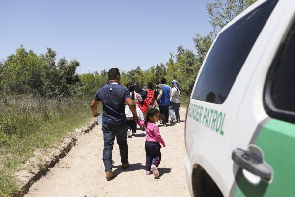 A group of illegal aliens walk up the road after crossing the Rio Grande from Mexico. Further up the road, they will board a bus bound for the Border Patrol processing facility in McAllen, Texas, on April 18, 2019. (Charlotte Cuthbertson/The Epoch Times)