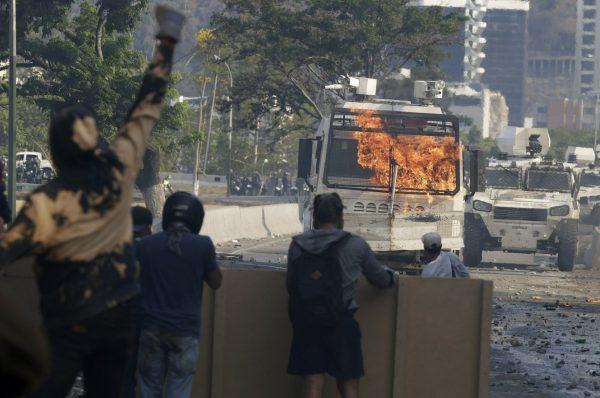 Flames erupts on a water cannon vehicle after anti government demonstrators hit it with a gasoline bomb during clashes with security forces loyal to President Nicolás Maduro in Caracas, Venezuela, on May 1, 2019. (Martin Mejia/AP Photo)