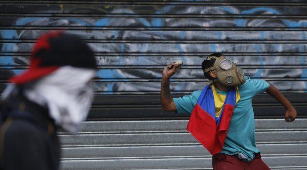 An anti-government protester winds up to throw a rock at security forces during clashes between the two, in Caracas, Venezuela, on May 1, 2019. (Fernando Llano/AP Photo)
