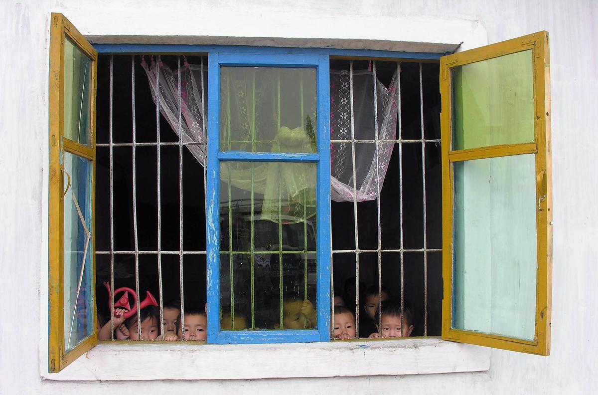 North Korean children peer through a window at a government-run nursery on July 20, 2005. (Gerald Bourke/World Food Program via Getty Images)
