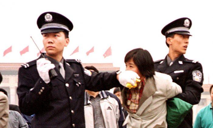 Two Chinese police officers arrest a female Falun Gong practitioner at Tiananmen Square in Beijing on Jan. 10, 2000. The persecution of Falun Gong has continued for nearly 20 years. (©AP | Chien-Min Chung)