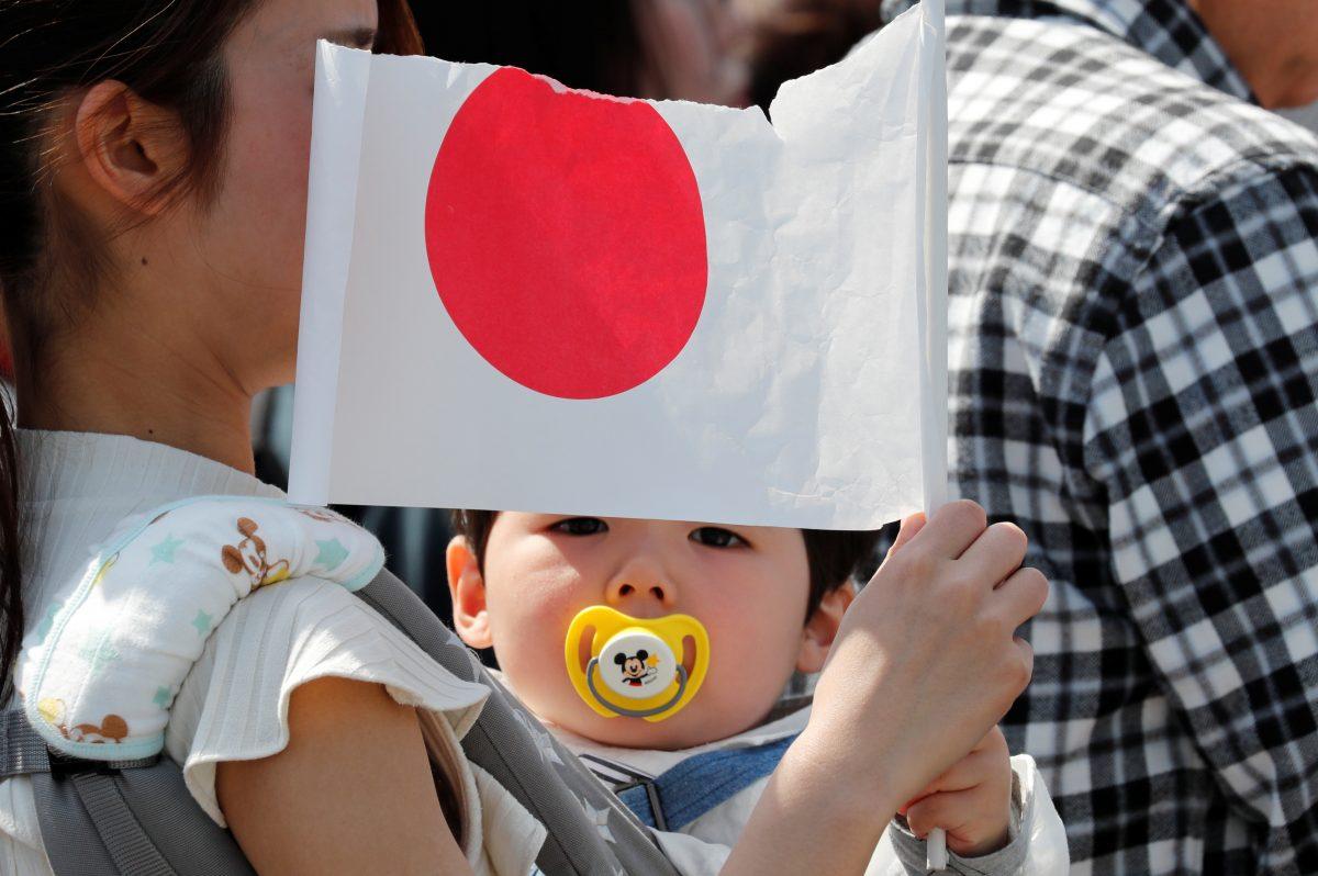 A baby holds a Japanese national flag outside the royal palace before the first public appearance of Japan's head of state Naruhito and his wife Masako in Tokyo, Japan, on May 4, 2019. (Kim Kyung-Hoon/Reuters)