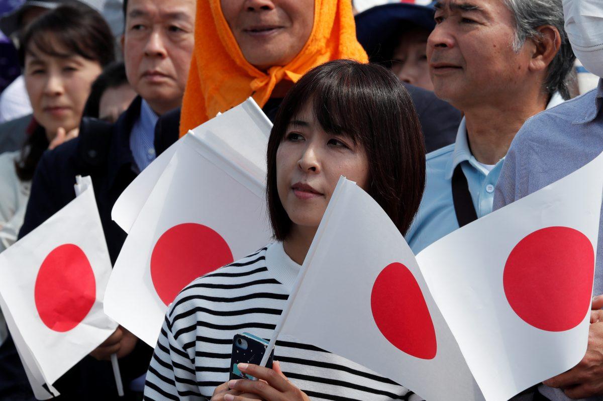 A woman holds a flag as she waits in line to enter the royal palace before the first public appearance of Japan's head of state Naruhito and his wife Masako in Tokyo, Japan, on May 4, 2019. (Kim Kyung-Hoon/Reuters)