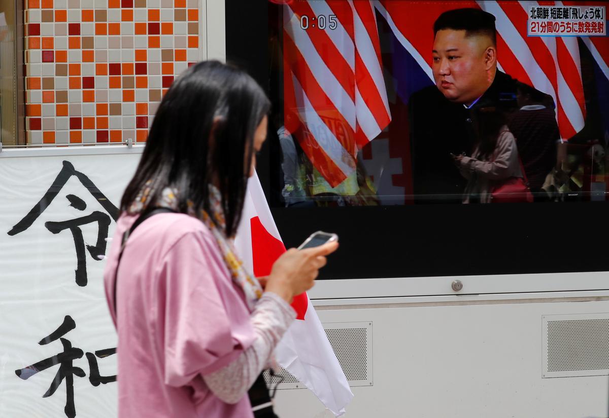 A woman walks past a sign printed with the characters of the name of the new Japanese imperial era Reiwa next to a television screen showing North Korea's leader Kim Jong Un during a news report on North Korea firing several short-range projectiles from its east coast, in Tokyo, Japan, on May 4, 2019. (Reuters/Kim Kyung-Hoon)