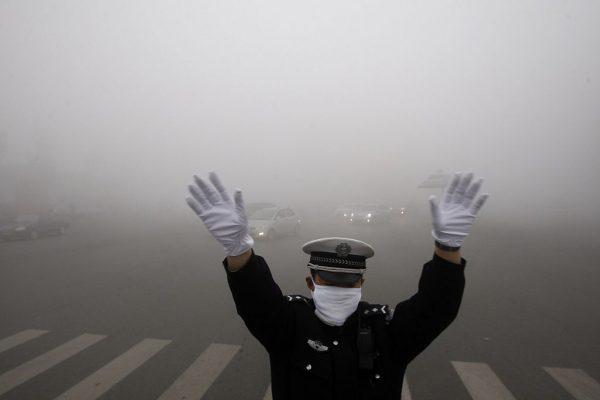 A policeman gestures as he works on a street in heavy smog in Harbin, northeast China's Heilongjiang Province, on Oct. 21, 2013. (STR/AFP/Getty Images)