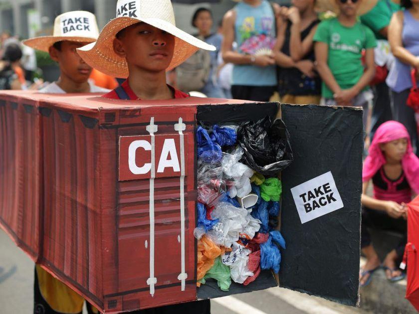 Filipino environmental activists wear a mock container vans filled with garbage to symbolize the 50 containers of waste that were shipped from Canada to the Philippines two years ago, at the Canadian embassy in Makati, south of Manila, Philippines on May 7, 2015. (Aaron Favila/The Associated Press)