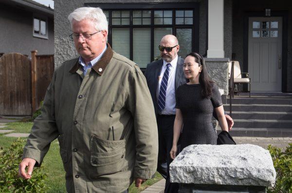 Huawei chief financial officer Meng Wanzhou, back right, is accompanied by a private security detail as she leaves her home to attend a court appearance in Vancouver on May 8, 2019. (The Canadian Press/Darryl Dyck)