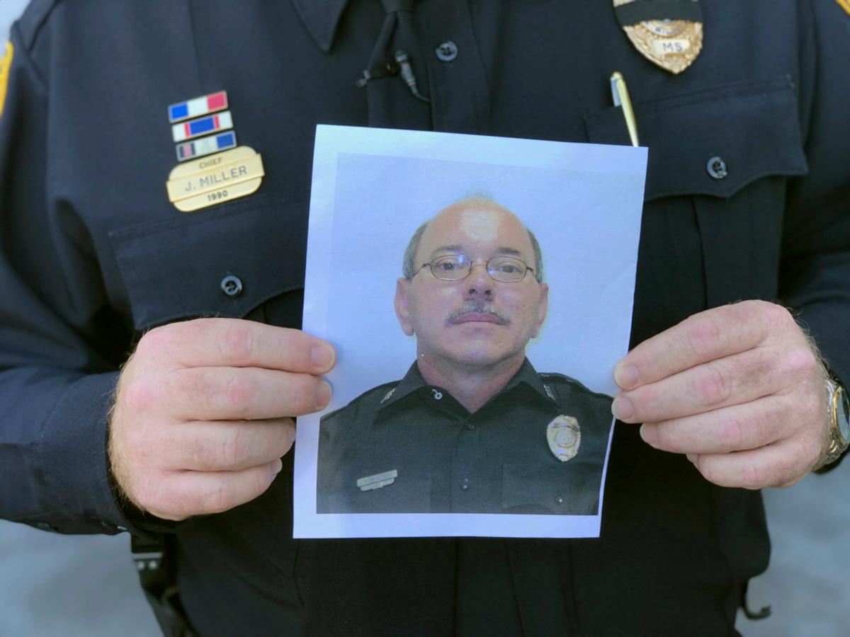 Biloxi Police Chief John Miller holds a departmental photograph of Officer Robert McKeithen. (Justin Mitchell/The Sun Herald via AP)
