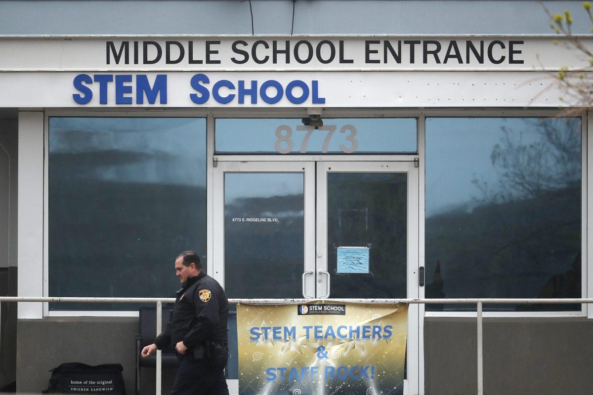 A Douglas County, Colo., Sheriff's Department deputy walks past the doors to the STEM Highlands Ranch school early Wednesday, May 8, 2019, in Highlands Ranch, Colo. Two high school students used at least two handguns in a fatal shooting on Tuesday at the charter school, authorities said Wednesday. (AP Photo/David Zalubowski)