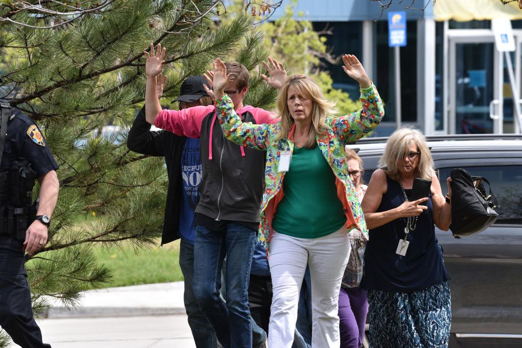 Students and teachers raise their arms as they exit the scene of a shooting in which at least seven students were injured at the STEM School Highlands Ranch on May 7, 2019, in Highlands Ranch, Colo. (Photo by Tom Cooper/Getty Images)
