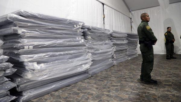 A Border Patrol agent stands near a stack of mattresses during a media tour of a new U.S. Customs and Border Protection temporary facility near the Donna International Bridge in Donna, Texas, on May 2, 2019. (Eric Gay/Photo via AP)