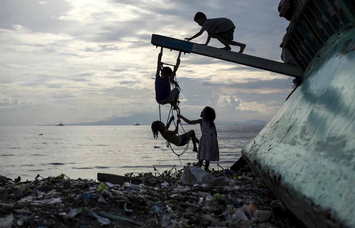 Filipino children play at a broken fishing boat in Manila Bay in Baseco, Tondo on July 8, 2017. (Noel Celis/AFP/Getty Images)