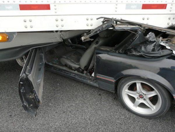 A wrecked mustang under a semi-trailer on the I-69 highway in Indiana on May 12, 2019. (Indiana State Police)