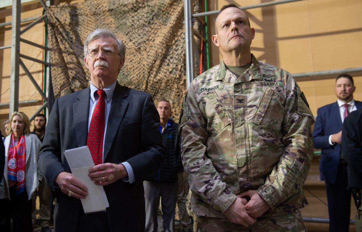 National security adviser John Bolton (L) listens as President Donald Trump speaks to members of the military during a trip to Al Asad Air Base in Iraq, on Dec. 26, 2018. (Saul Loeb/AFP/Getty Images)