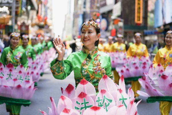 A Falun Dafa practitioner in lotus flower costume waves during a parade celebrating World Falun Dafa Day in Manhattan, New York, on May 16, 2019. (Edward Dye/The Epoch Times)