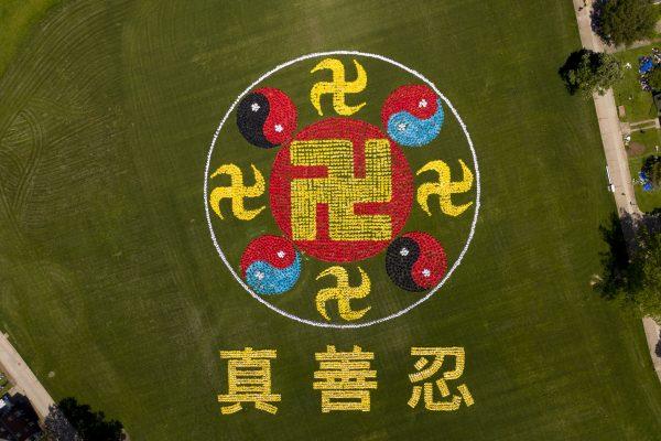 An aerial view of the falun emblem and characters for truthfulness, compassion, and forbearance, formed by practitioners of the spiritual discipline Falun Gong, on Governors Island, N.Y., on May 18, 2019. (NTD)