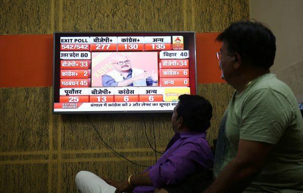 Men look at a television screen showing exit poll results after the last phase of the general election in Ahmedabad, India, on May 19, 2019. (Amit Dave/Reuters)