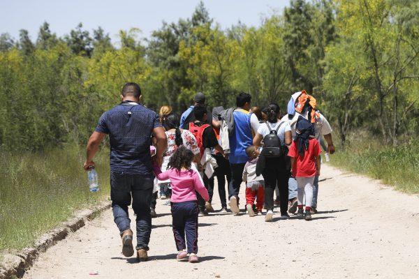 A group of illegal aliens walk up the road after crossing the Rio Grande from Mexico. Further up the road, they will board a bus bound for the Border Patrol processing facility in McAllen, Texas, on April 18, 2019. (Charlotte Cuthbertson/The Epoch Times)