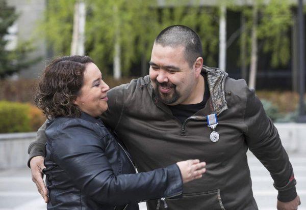 Nome Magistrate Judge Pamela Smith gets a hug from her friend, George "Radar" Lambert after Lambert was given a Silver Lifesaving Medal at the Atwood Building courtyard in Anchorage, Alaska.On May 18, 2019. (Loren Holmes/Anchorage Daily News via AP)