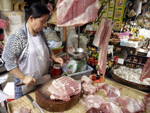 Vendor Khov Sokhouy, 56, cuts pork to sell to customers at the Phsar Kandal market in Phnom Penh, Cambodia on May 16, 2019. Potential shortages are a more serious concern in places such as Cambodia where pork is the only meat many families can afford. (Heng Sinith/AP)