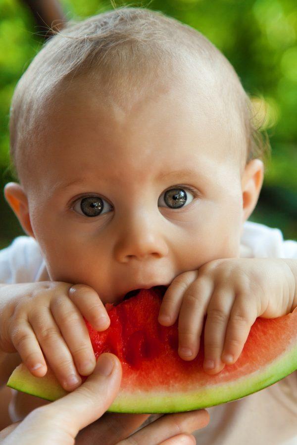 A baby eats a piece of watermelon. (Pixabay)