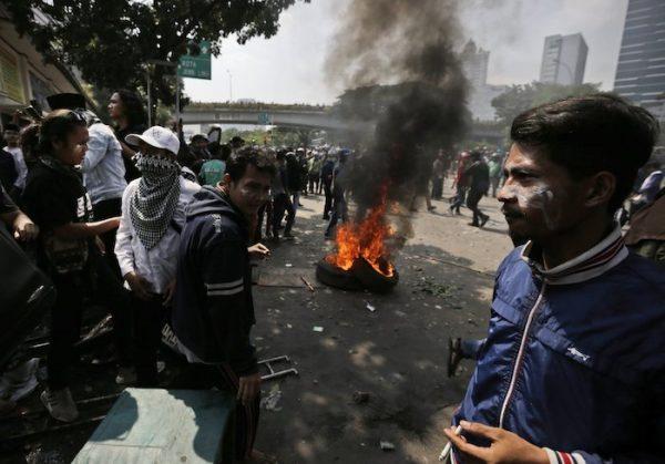 Protesters rest near burning tires during a clash with the police in Jakarta, Indonesia, on May 22, 2019. (Dita Alangkara/AP Photo)