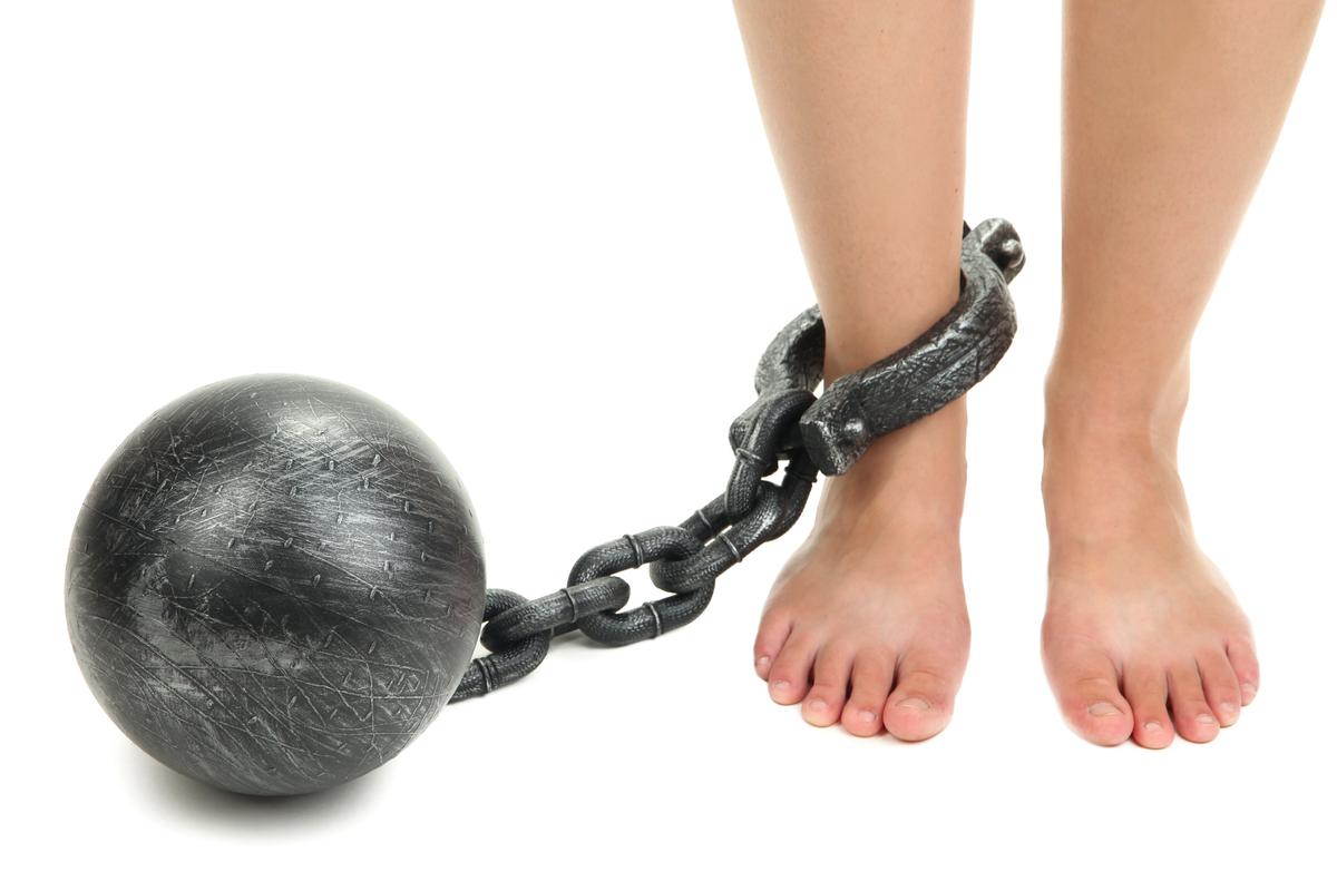 Illustration - Shutterstock | <a href="https://www.shutterstock.com/image-photo/legs-heavy-iron-shackles-isolated-on-150986522">Africa Studio</a>