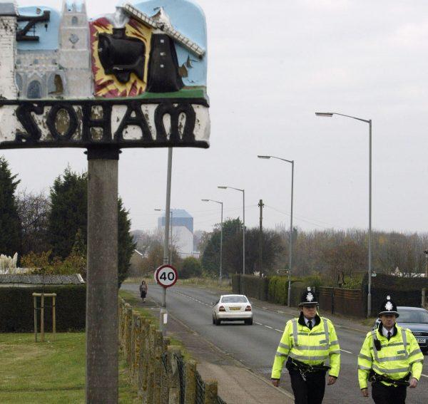 File photo showing two police officers walking past the sign welcoming visitors to the village of Soham, in Soham, England on Nov. 10, 2003. (Graeme Robertson/Getty Images)