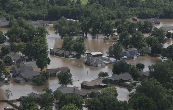 In this aerial image, homes are inundated with flood waters from the Arkansas River near South 145th West Ave near Highway 51 in Sand Springs, Okla., on May 23, 2019. (Tom Gilbert/Tulsa World via AP)