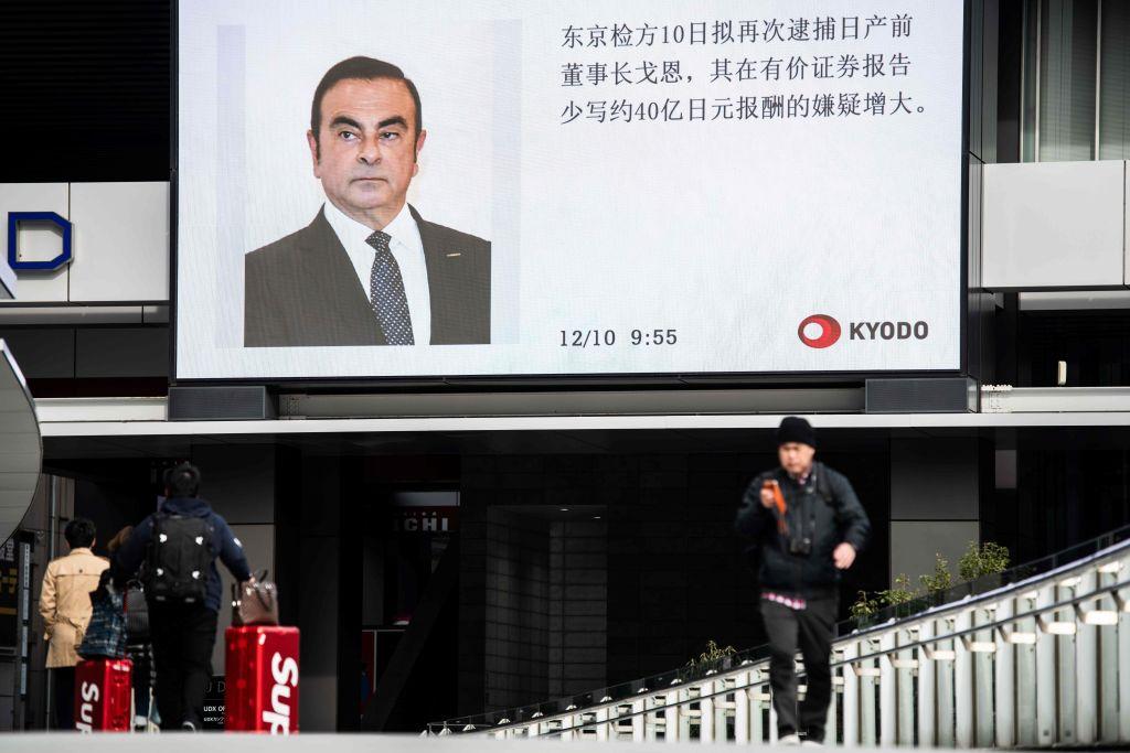 Pedestrians walk past a television screen showing a news programme featuring former Nissan chief Carlos Ghosn in Tokyo on Dec. 10, 2018. (Martin Bureau/AFP/Getty Images)