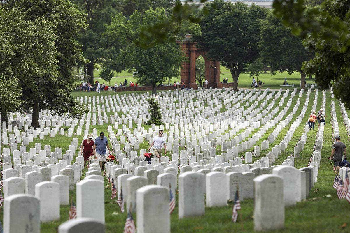 Volunteers place flowers at tombstones in Arlington Cemetery in Arlington, Va., on May 26, 2019. (Samira Bouaou/The Epoch Times)