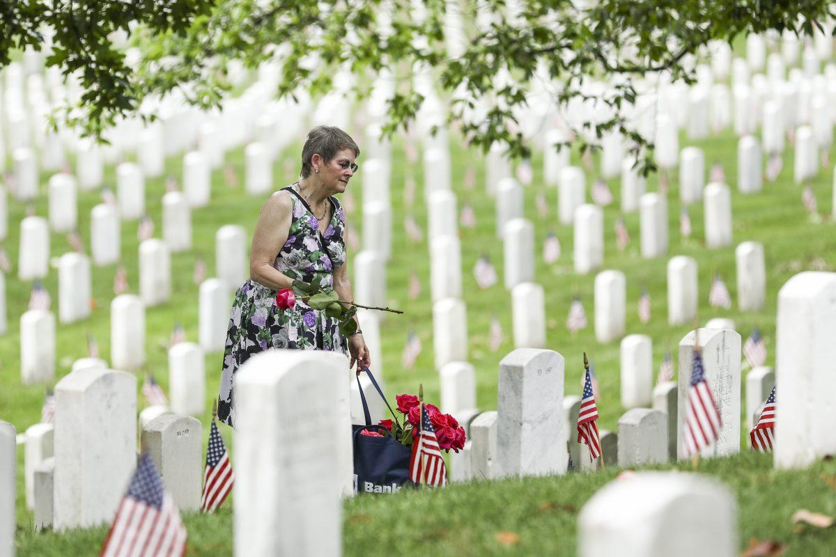 A woman places roses and thanks the servicemen in Arlington Cemetery in Arlington, Va., on May 26, 2019. (Samira Bouaou/The Epoch Times)