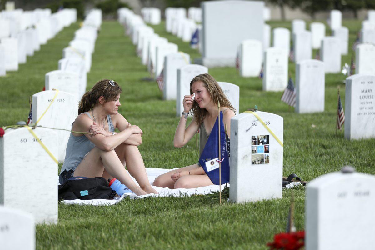 Krista Meinert (L), mother, and Randy Meinert, sister of Jacob Alexander Meinert, LCPL U.S. Marine Corps, sit at his grave in Arlington Cemetery in Arlington, Va., on May 26, 2019. (Samira Bouaou/The Epoch Times)