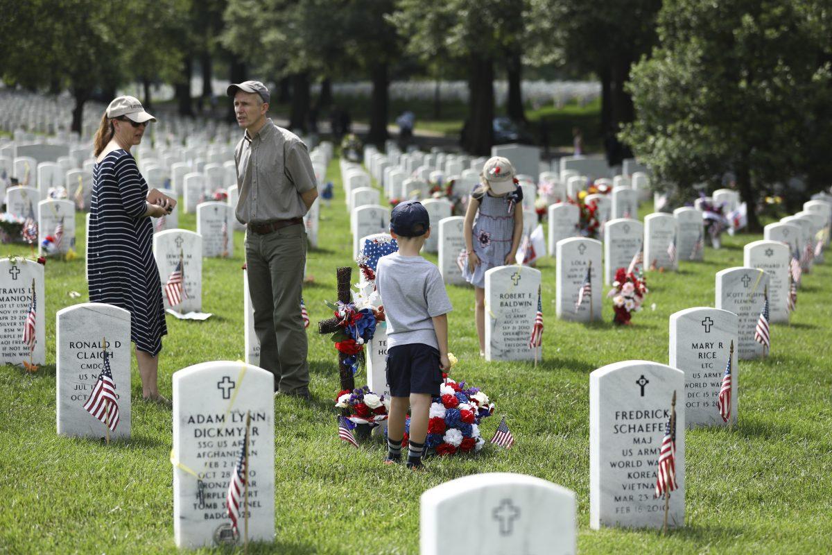 A family pays their respects at the tombs of fallen servicemen at Arlington Cemetery in Arlington, Va., on May 26, 2019. (Samira Bouaou/The Epoch Times)