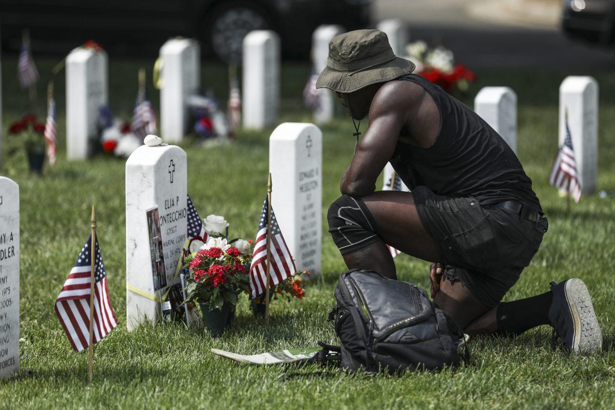 A man pays respects to a fallen soldier in Arlington Cemetery in Arlington, Va., on May 26, 2019. (Samira Bouaou/The Epoch Times)