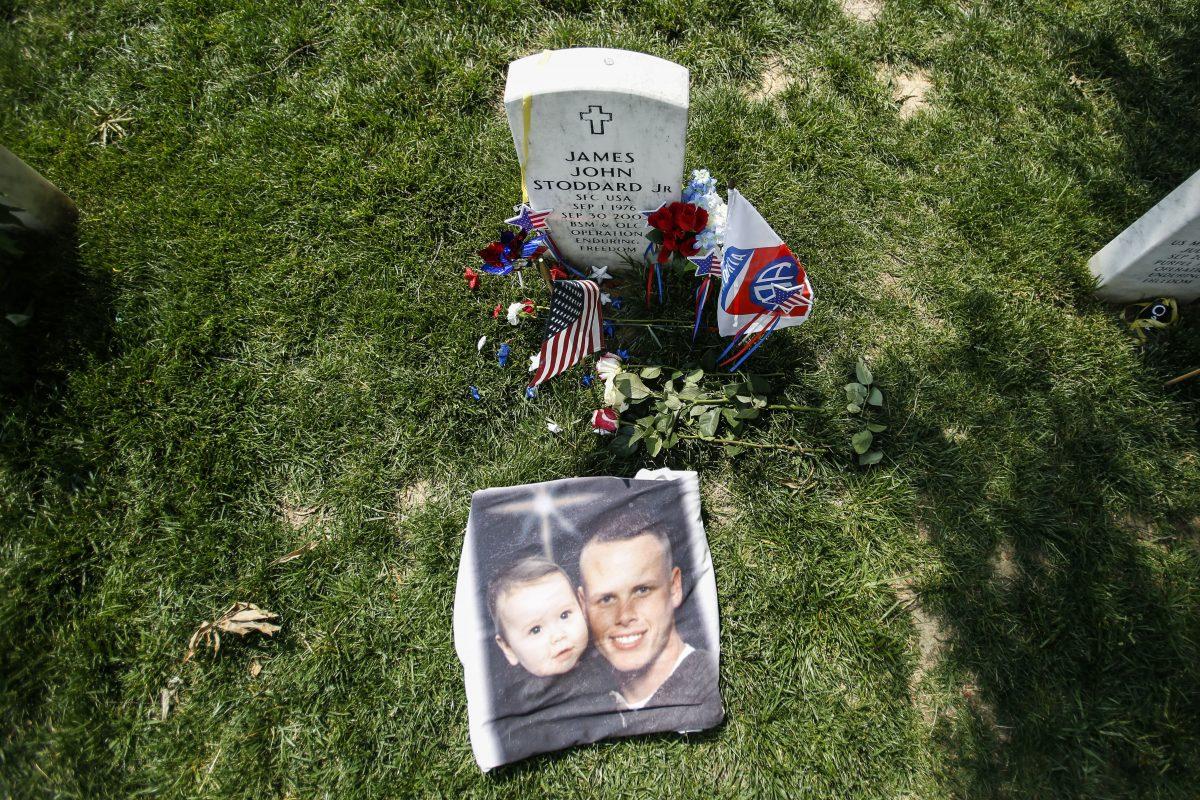 A picture of James J. Stoddard, Jr., Sergeant First Class, United States Army, with his son lays next to his grave at the Arlington Cemetary in Arlington, Va., on May 2019. They have three children. (Samira Bouaou/The Epoch Times)