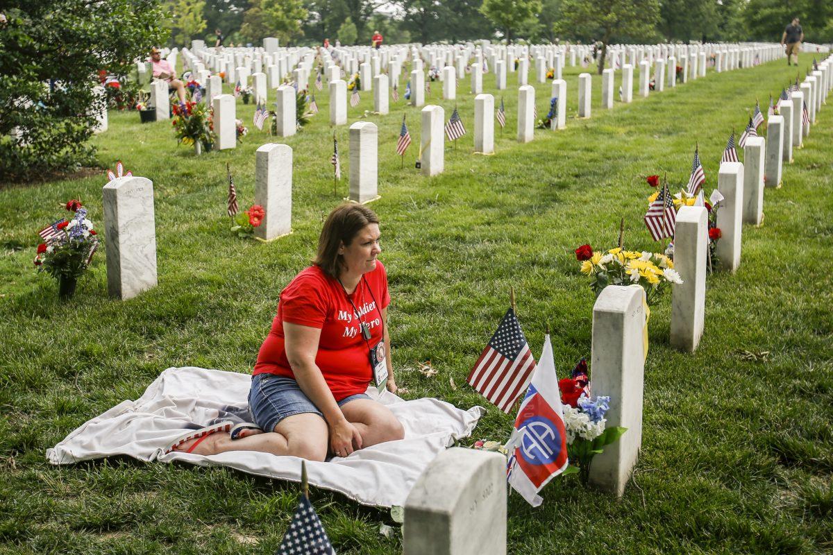 Amy Stoddard, spouse of James J. Stoddard, Jr., Sergeant First Class, United States Army, sits at his grave at the Arlington Cemetary in Arlington, Va., on May 2019. They have three children. (Samira Bouaou/The Epoch Times)