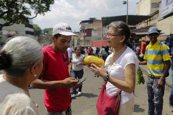 A woman bargains for a papaya with a street vendor in Caracas, Venezuela, on April 10, 2019. (Eva Marie Uzcategui/Getty Images)