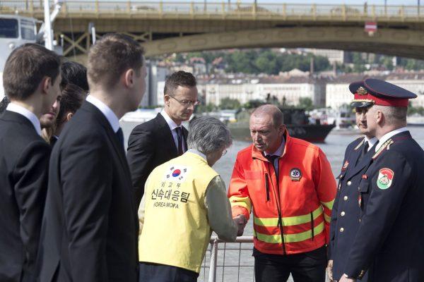 Kang Kyung-wha, center, foreign minister of South Korea, shakes hands with a member of a rescue team as she visits the bank of the Danube River where a sightseeing boat capsized in Budapest, Hungary, on May 31, 2019. (Marko Drobnjakovic/AP Photo)