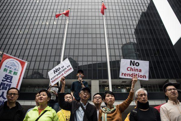 Hong Kong pro-democracy legislator Claudia Mo (center R) and bookseller Lam Wing-kee (center L) display placards outside the government headquarters during a rally in Hong Kong on March 31, 2019 to protest against the government's plans to approve extraditions with mainland China, Taiwan and Macau. (Dale De La Rey/AFP/Getty Images)