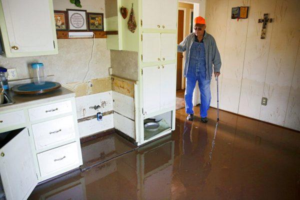 In this photo, Eugene Bowers looks at the kitchen in his flooded home in the Town and Country neighborhood west of Sand Springs, Okla., on May 30, 2019. (Mike Simons/Tulsa World via AP)