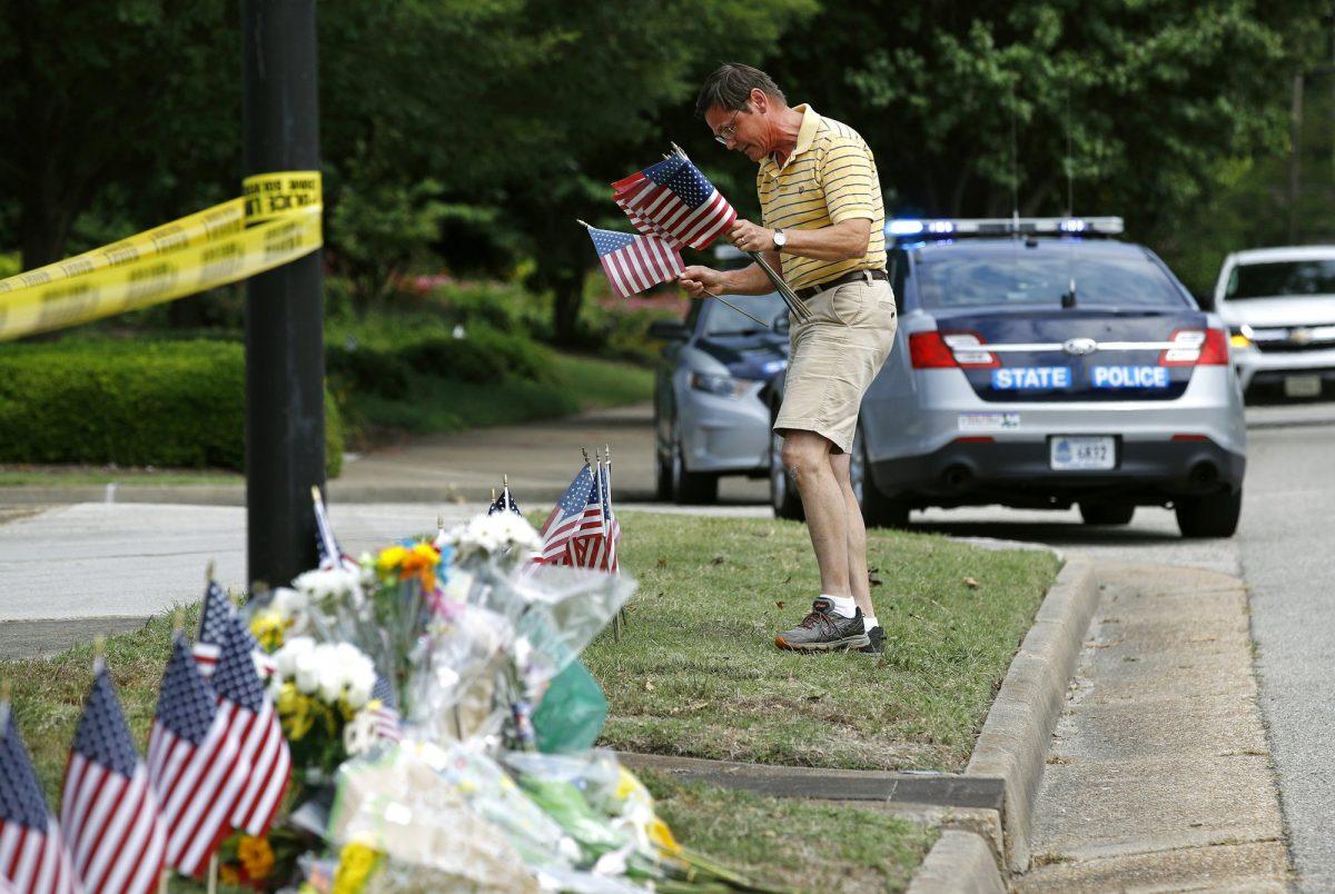 Rich Lindgren, of Virginia Beach, Va., places American flags at a makeshift memorial at the edge of a police cordon in front of a municipal building that was the scene of a shooting in Virginia Beach, Va., on June 1, 2019. (Patrick Semansky/AP Photo)