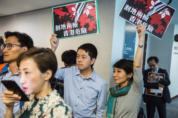 Pro-democracy lawmakers Ted Hui (C) of the Democratic Party and Claudia Mo (center R) of the Civic Party hold signs reading "ceding land with co-location puts Hong Kong in danger" at the Legislative Council building in Hong Kong on Aug. 3, 2017. (Isaac Lawrence/AFP/Getty Images)