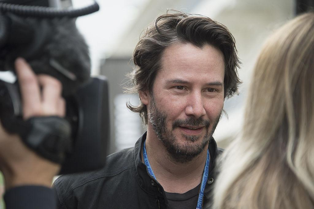 Reeves being interviewed at the MotoGp Red Bull U.S. Grand Prix in Austin, Texas, in 2016 (©<a href="https://www.gettyimages.com/detail/news-photo/keanu-reeves-of-canada-speaks-with-journalist-in-paddock-news-photo/520344668?adppopup=true">Getty Images</a>)