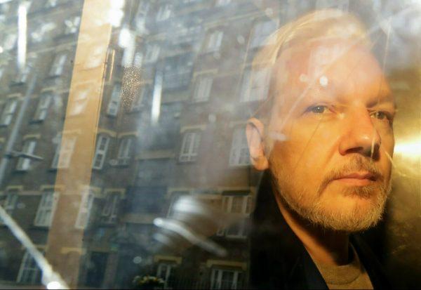 Buildings are reflected in the window as WikiLeaks founder Julian Assange is taken from court, where he appeared on charges of jumping British bail, in London on May 1, 2019. (Matt Dunham/AP)